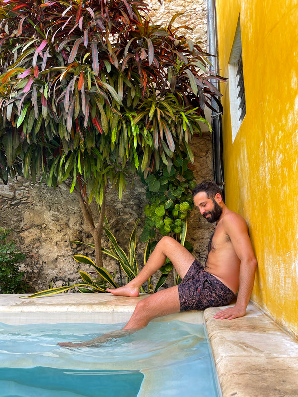 Copper Bottom Swim - man in black and gold swim shorts sitting in pool